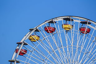 photography of yellow, red, and gray ferris wheel under blue sky