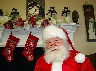 man wears white and red Santa Claus costume beside two red Christmas stockings