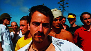 man wearing white collared top beside group of men under blue sky during daytime