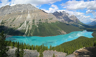 gray and green mountain with teal calm body of water during daytime