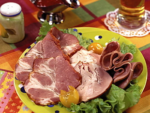 sliced ham with green leaf vegetable and tomato on green ceramic plate