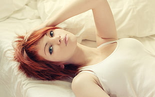woman wearing white tank top lying on bed