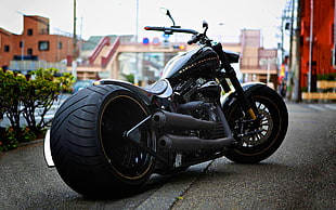 shallow focus photography  of black cruiser motorcycle park on street during daytime