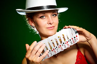 woman wearing pink spaghetti strap top while holding playing card deck