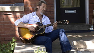 man wearing white dress shirt holding brown guitar