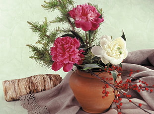 two red and white flower arrangement in brown mud vase