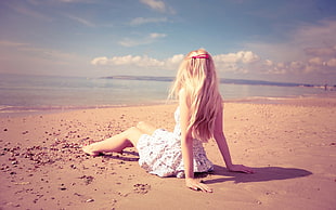 woman wearing white dress sitting on brown beach