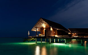 brown wooden hut on water with lights HD wallpaper
