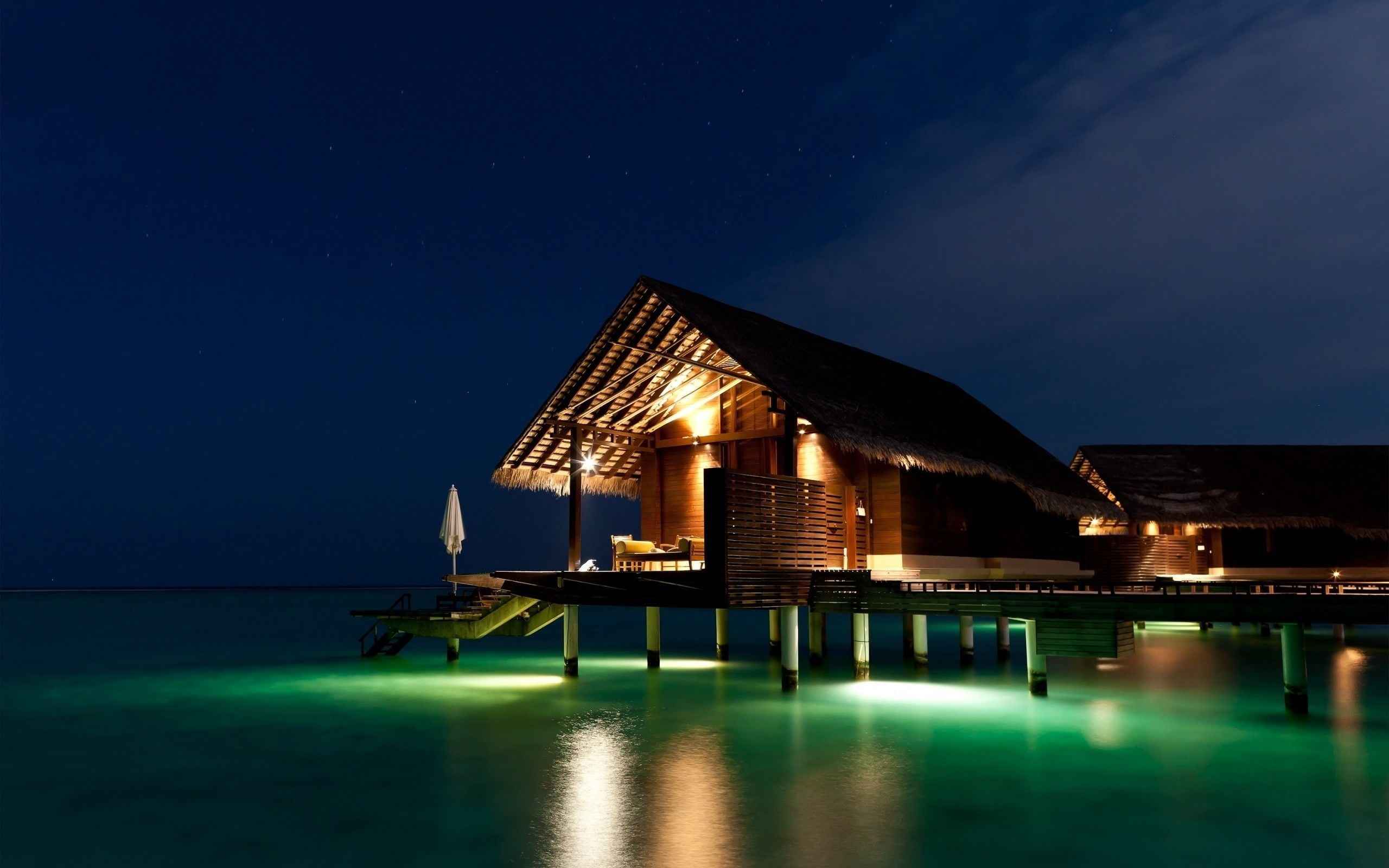 brown wooden hut on water with lights