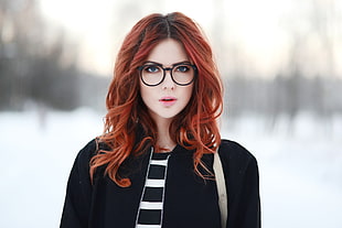 woman with eyeglasses and black zip-up jacket on snow ground