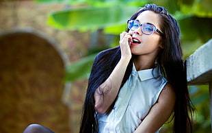woman in white buttoned-up sleeveless top wearing black frame eyeglasses