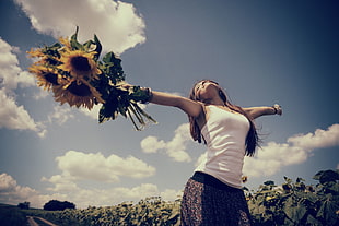 selective focus photography of woman holding sunflower