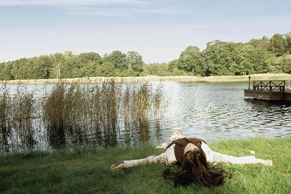 woman lying on grass beside the river HD wallpaper