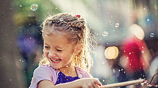 girl in pink cardigan plays with water during daytime