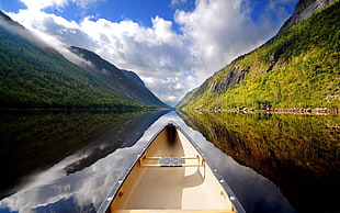 landscape photography of canoe in between green mountains during daytime