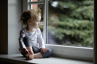 child sitting near glass window