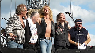 group on 5 men standing on stage near microphone