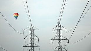 two black steel electric posts, power lines, hot air balloons, utility pole