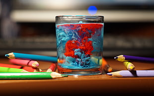 tilt shift focus photography of drinking glass with red and blue color inside decor