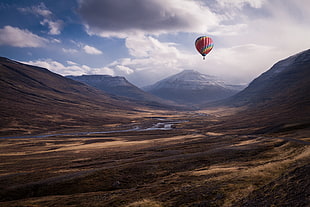 hot air balloon flying over mountains during daytime HD wallpaper