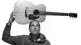 gray scale photo of man with acoustic guitar on head