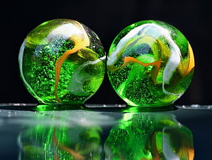 two green-and-yellow marble balls