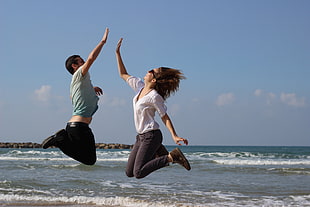 man and woman jumping with hand gesture