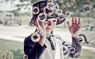 selective focus photography of girl catching bubbles during daytime