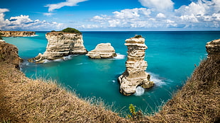 rock monolith surrounded by body of water under blue sky, Torre, puglia, italy HD wallpaper