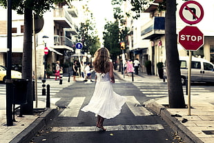 woman in white dress crossing in three street