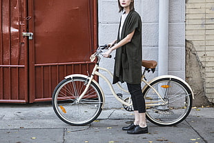woman standing beside cruiser bike near brown metal gate