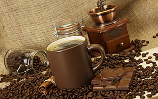 filled brown ceramic mug beside chocolate bar