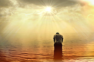 silhouette of man on body of water during sun rays