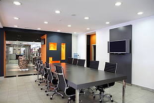 empty conference room with wooden table, chairs and wall-mounted flat screen TV