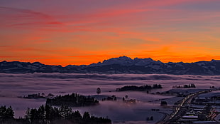 aerial view of city covered in fog at golden hour, sunset, mountains, highway, clouds