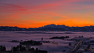 aerial view of city covered in fog at golden hour, sunset, mountains, highway, clouds