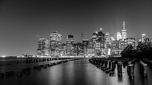 greyscale photo of calm body of water overlooking city at nighttime