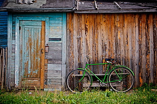 photo of green road bike near brown wooden house