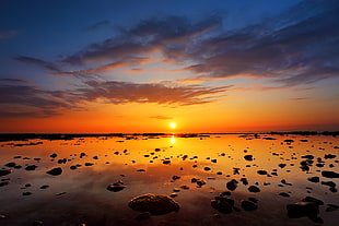 wide photography of a bodies of water with rocks and sunset background HD wallpaper