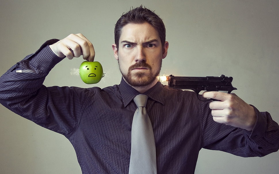 man in black dress shirt holding green apple and pistol HD wallpaper
