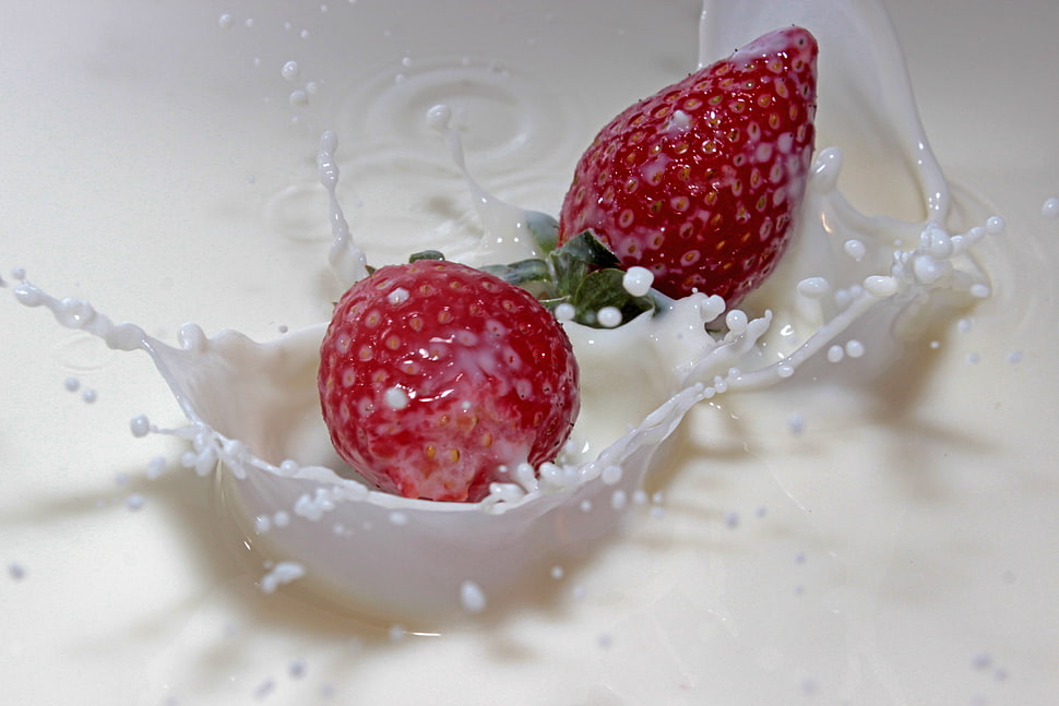 two strawberry fruits on milk HD wallpaper