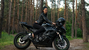 woman riding black Kawasaki Ninja sports bike in forest during daytime HD wallpaper