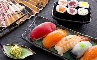 platter of sushi with wasabi near hand fan