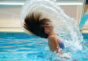 women splashing her hair in pool
