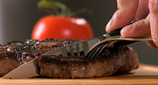 person cutting meat using knife and fork
