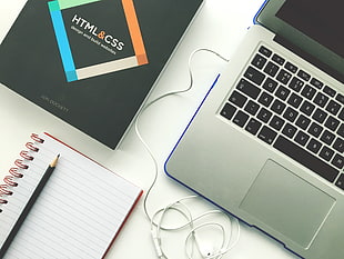 silver and black laptop near white spiral notebook with black pencil