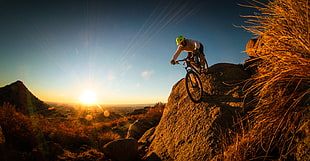 man  riding bicycle on mountain under golden hour