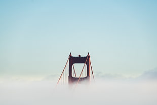 brown bridge on top of clouds during daytime HD wallpaper
