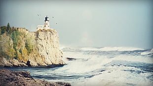 Lighthouse beside ocean during daytime HD wallpaper