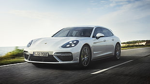 white Porsche Panamera running on road by the sea